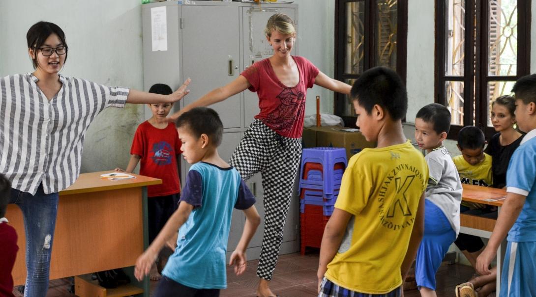 Childcare volunteers in Vietnam teach balancing exercises to a group of children at their placement. Projects Abroad volunteers demonstrate balancing exercises to a group of children at a care centre in Vietnam to develop co-ordination skills.